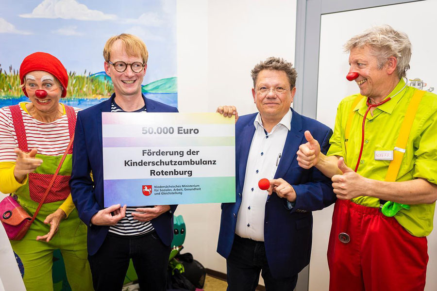 Zwei Clowns, Minister Dr. Andreas Philippi und Kinderklinik-Chefarzt Dr. Christof Kluthe präsentieren den Förderbescheid
