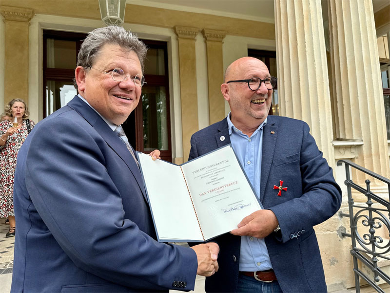 Minister Dr. Andreas Philippi gratuliert Johannes Schmidt mit Urkunde und Verdienstkreuz