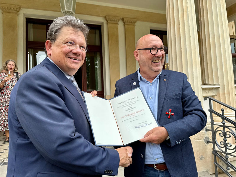 Minister Dr. Andreas Philippi gratuliert Johannes Schmidt mit Urkunde und Verdienstkreuz