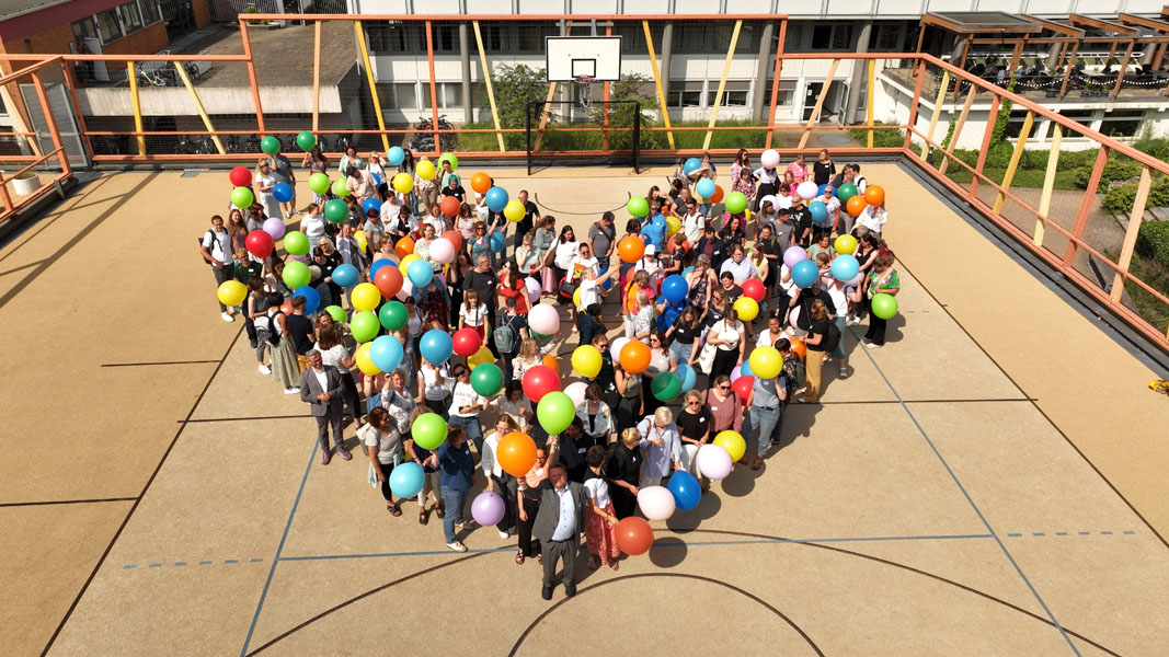 Blick von oben: 160 Teilnehmende mit Ballons bilden ein Herz