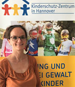 Anja Stiller steht vor einem Plakat der Kinderschutz-Zentrums Hannover