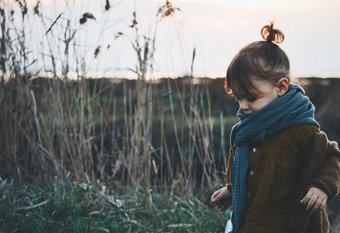 Kleines Mädchen mit dickem Schal und Strickjacke in Schilflandschaft, Foto: Caroline Hernandez | unsplash.com