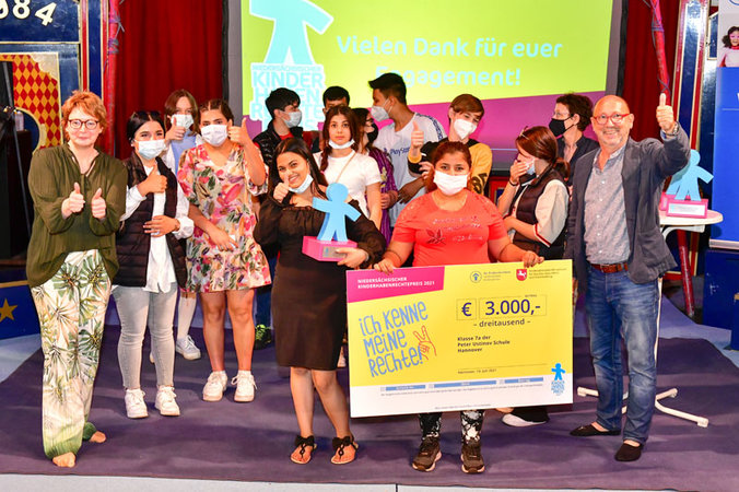 Teenager stehen mit der Ministerin und Johannes Schmidt in der Zirkusmanege und halten einen sehr großen Siegespreis-Scheck